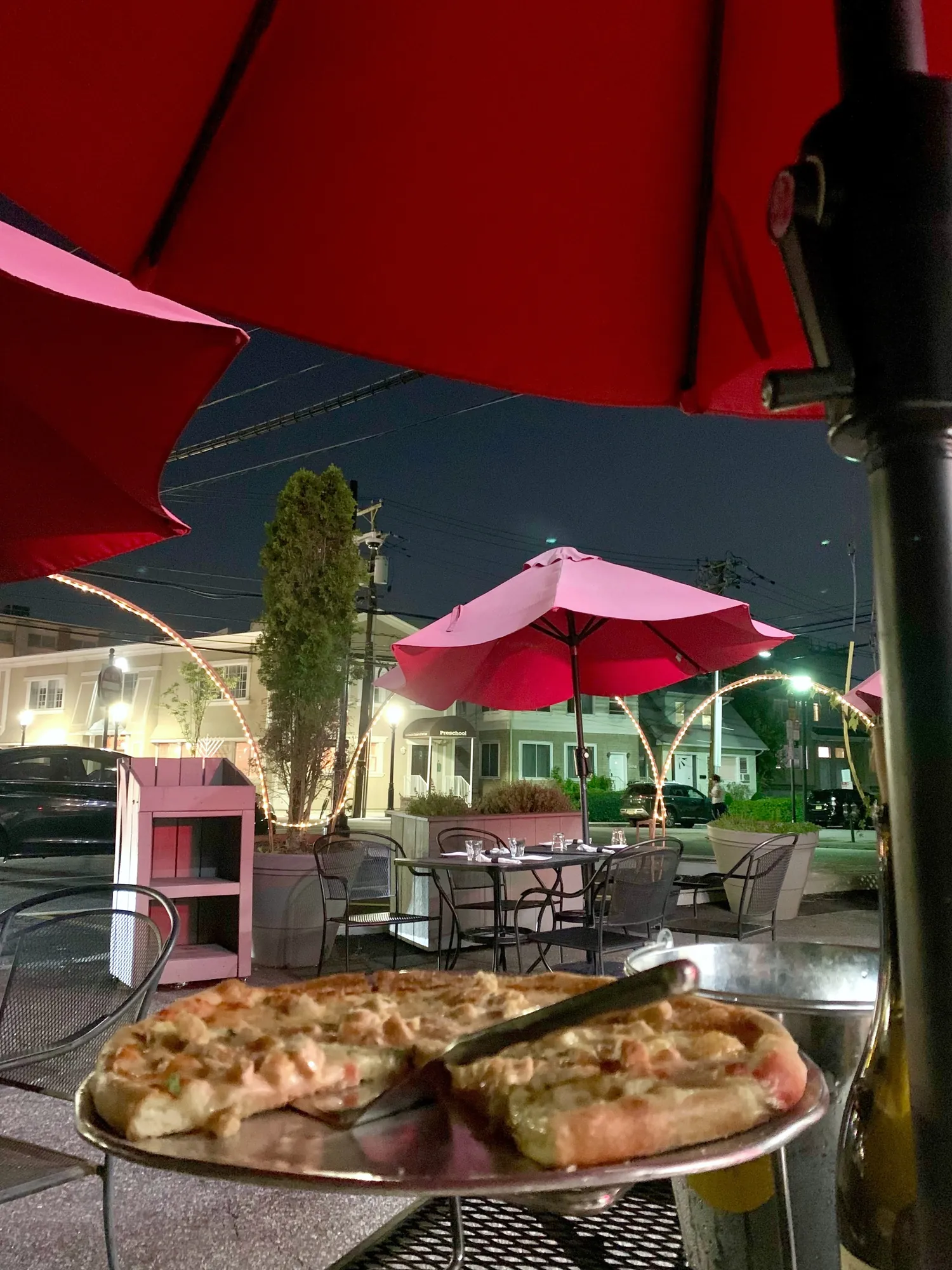A brick-oven pie on the patio at night, under the umbrellas